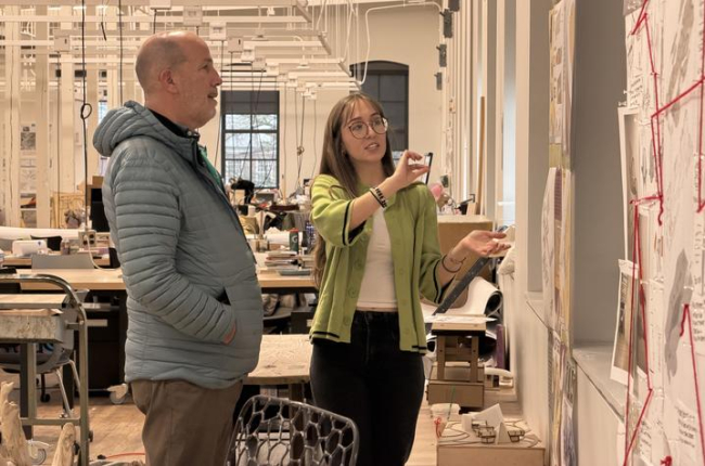 two people in a design studio review a project on a wall