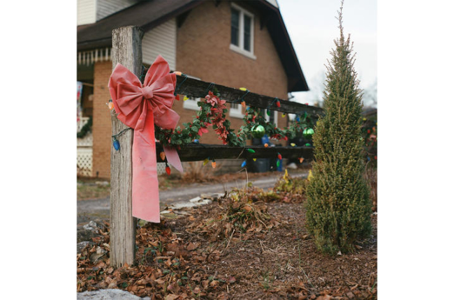 a wooden fence, decorated for winter holidays, in front of a brick house