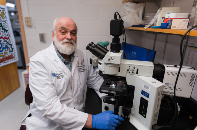 Brian Stevenson sits behind a microscope in his lab